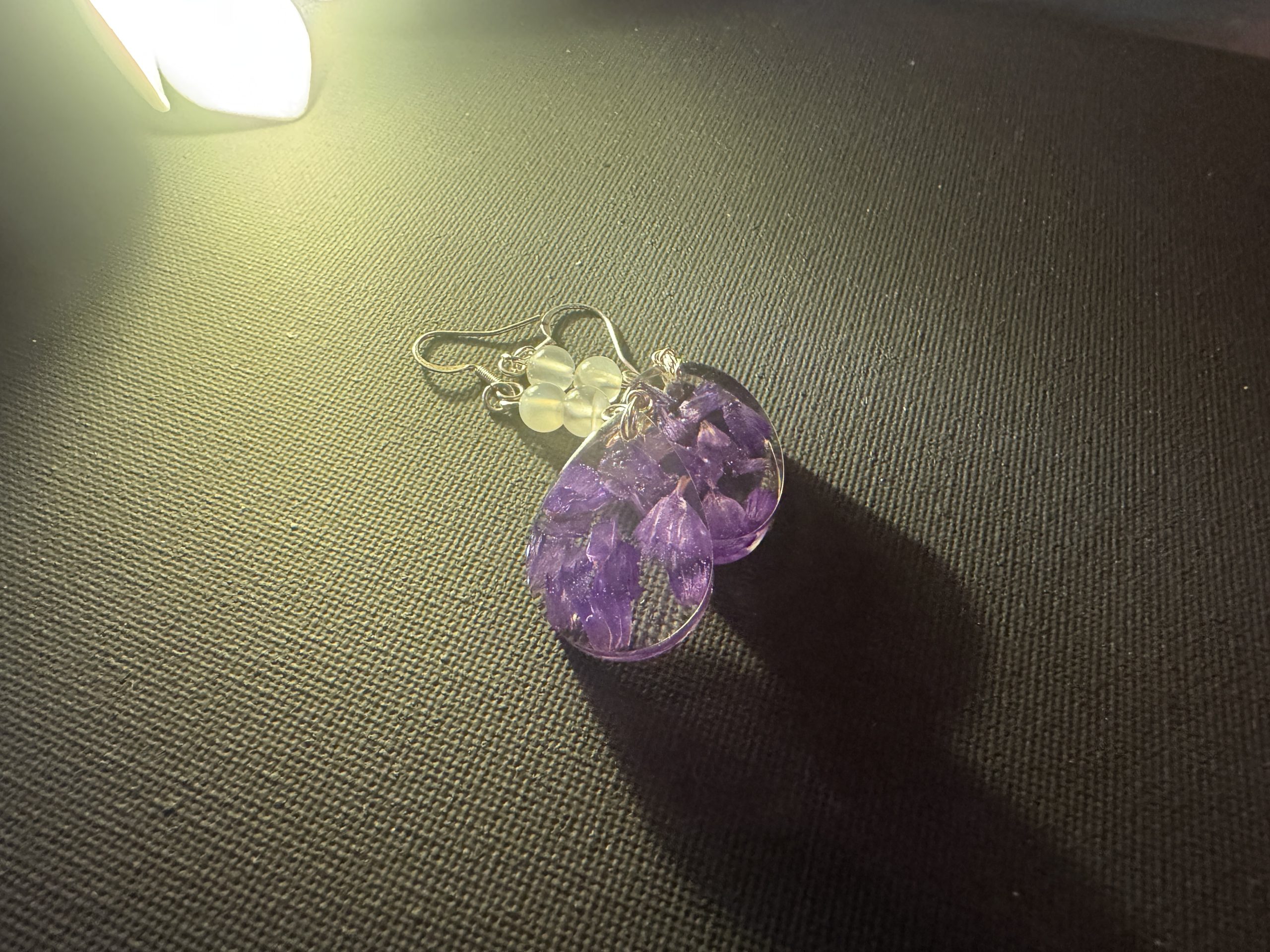 Earrings made from purple wildflowers cast in teardrops of crystal resin.