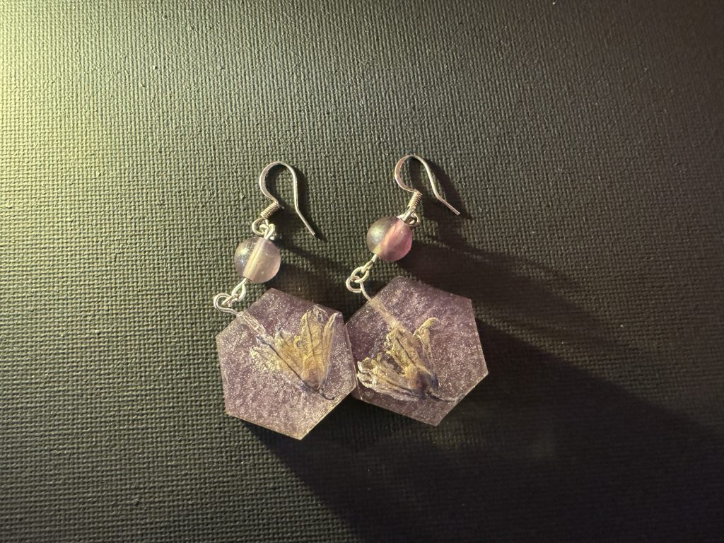 Sterling silver earrings with purple wildflowers in hexagonal resin medallions. Amethyst accent bead.